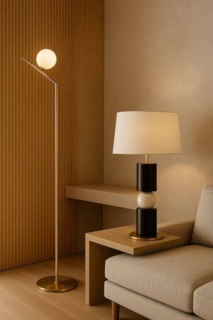 Lámpara de pie dorada y lámpara de sobremesa moderna con pantalla blanca sobre mesa auxiliar de madera, decorando un salón minimalista y elegante de Ao Mobiliario.