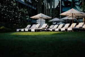 Tumbonas y muebles de exterior con sombrillas en jardín en Sevilla, ideales para terraza, piscina o patio. AO Mobiliario.